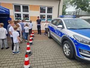 policjant z dziećmi stoi przy policyjnym radiowozie