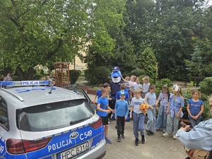 dzieci bawią się z policyjną maskotką