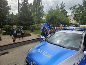 dzieci bawią się z policyjną maskotką