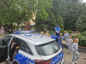 dzieci bawią się z policyjną maskotką