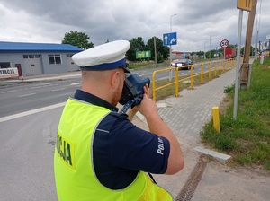 policjant mierzy prędkość pojazdów ręcznym miernikiem prędkości