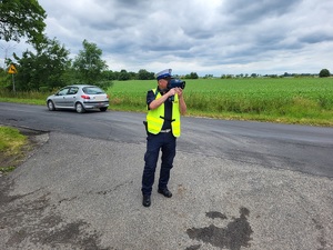 policjant mierzy prędkość jadącego pojazdu