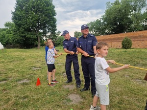 policjanci z dziećmi trzymają linę