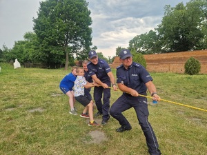 policjanci z chłopcami przeciągają linę