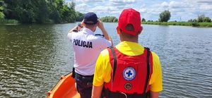 policjant i ratownik obserwują taflę jeziora