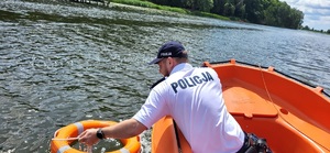 policjant wrzuca do wodu koło ratunkowe