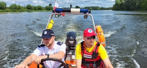 policjant i ratownik wodny płyną łodzią