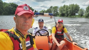 policjant i ratownicy wodni pozują do zdjęcia w łodzi